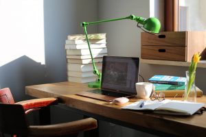 biurko z laptopem, książkami i notatnikiem